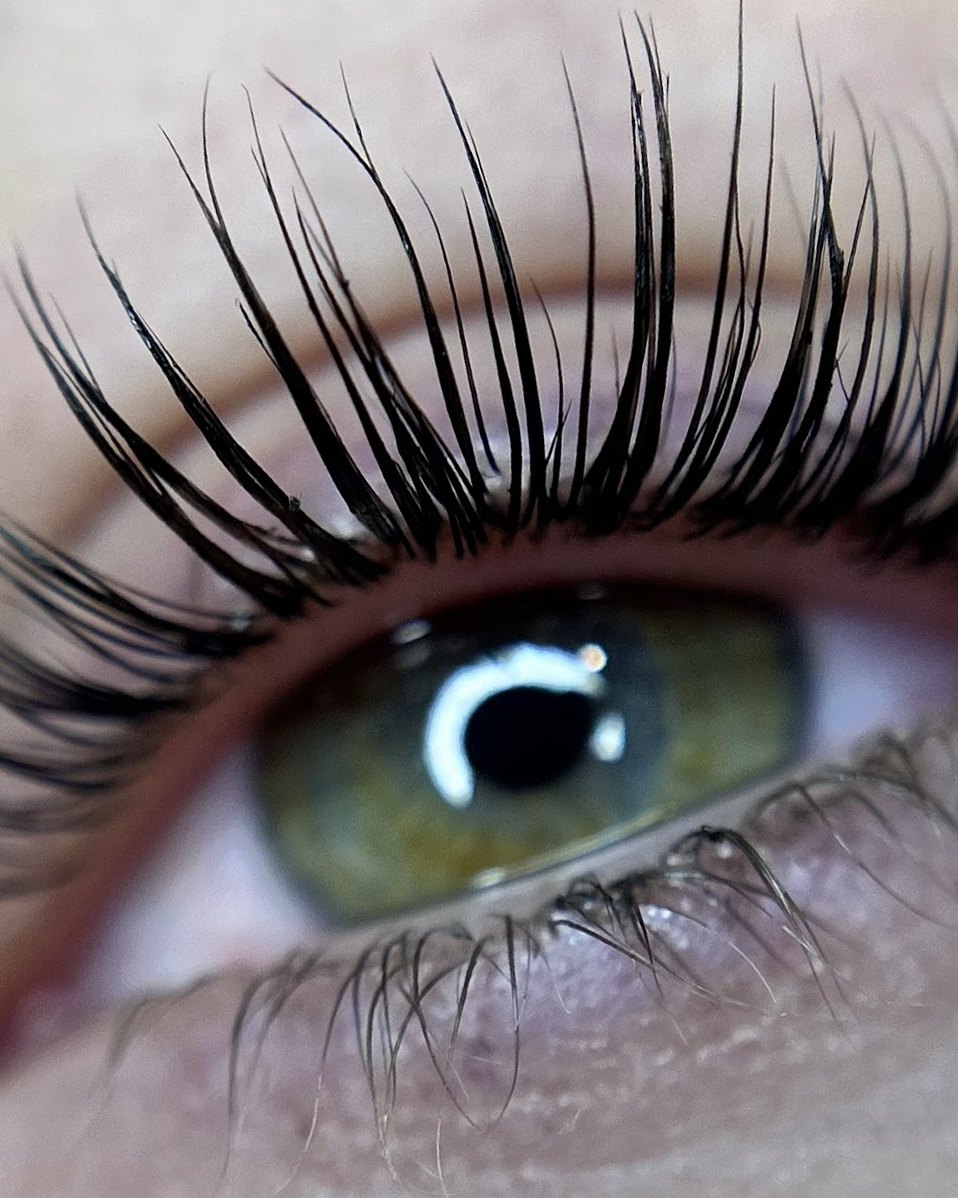 Gelifte wimpers boven een groen oog, van dichtbij